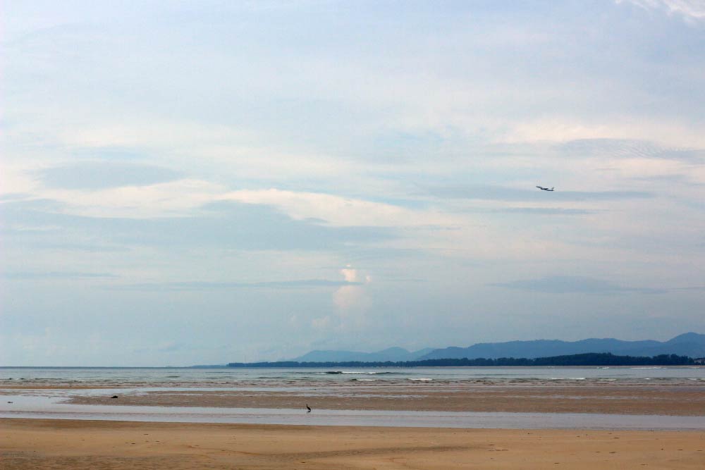 Вдалеке взлетает самолет. Вблизи можно посмотреть на пляже Май Кхао