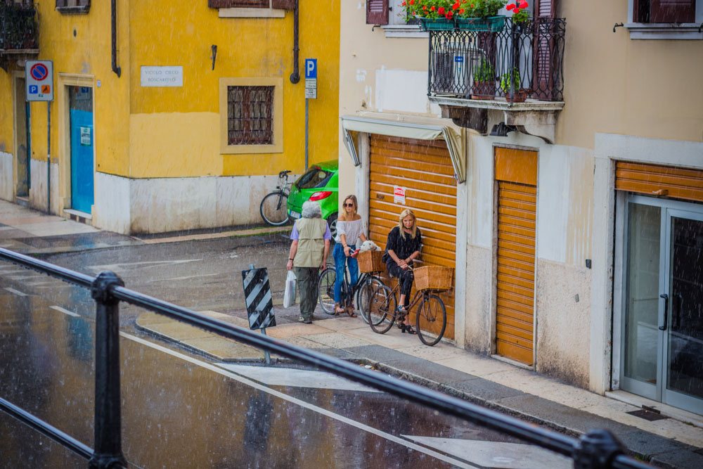 Две итальянки на велосипедах прячутся под дождем