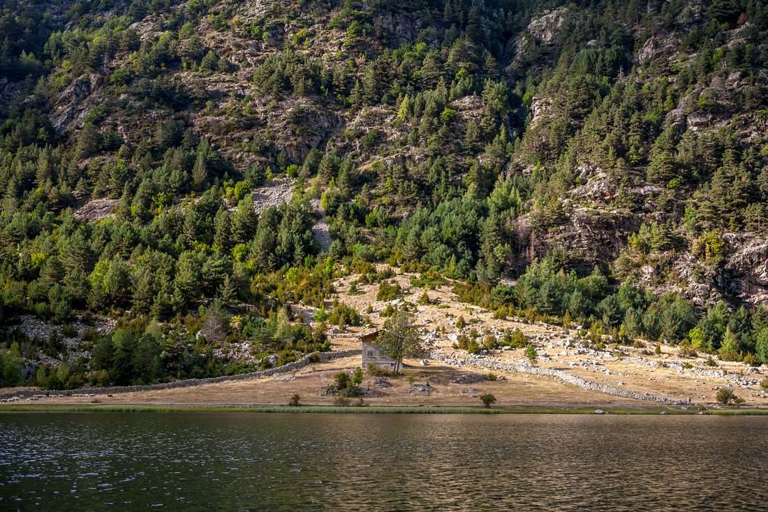 Одинокий домик на противоположном берегу озера Estany de la Llebreta