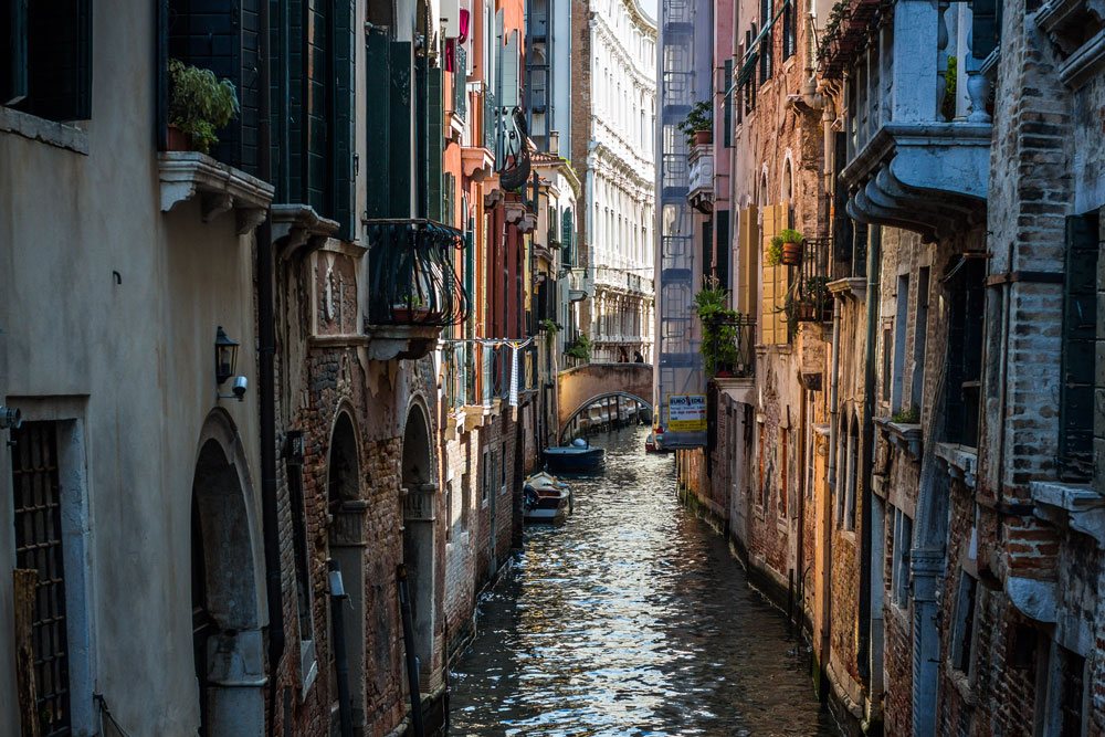 Узкий канал в Венеции без туристов и гондол, игра света и тени передают колорит улицы